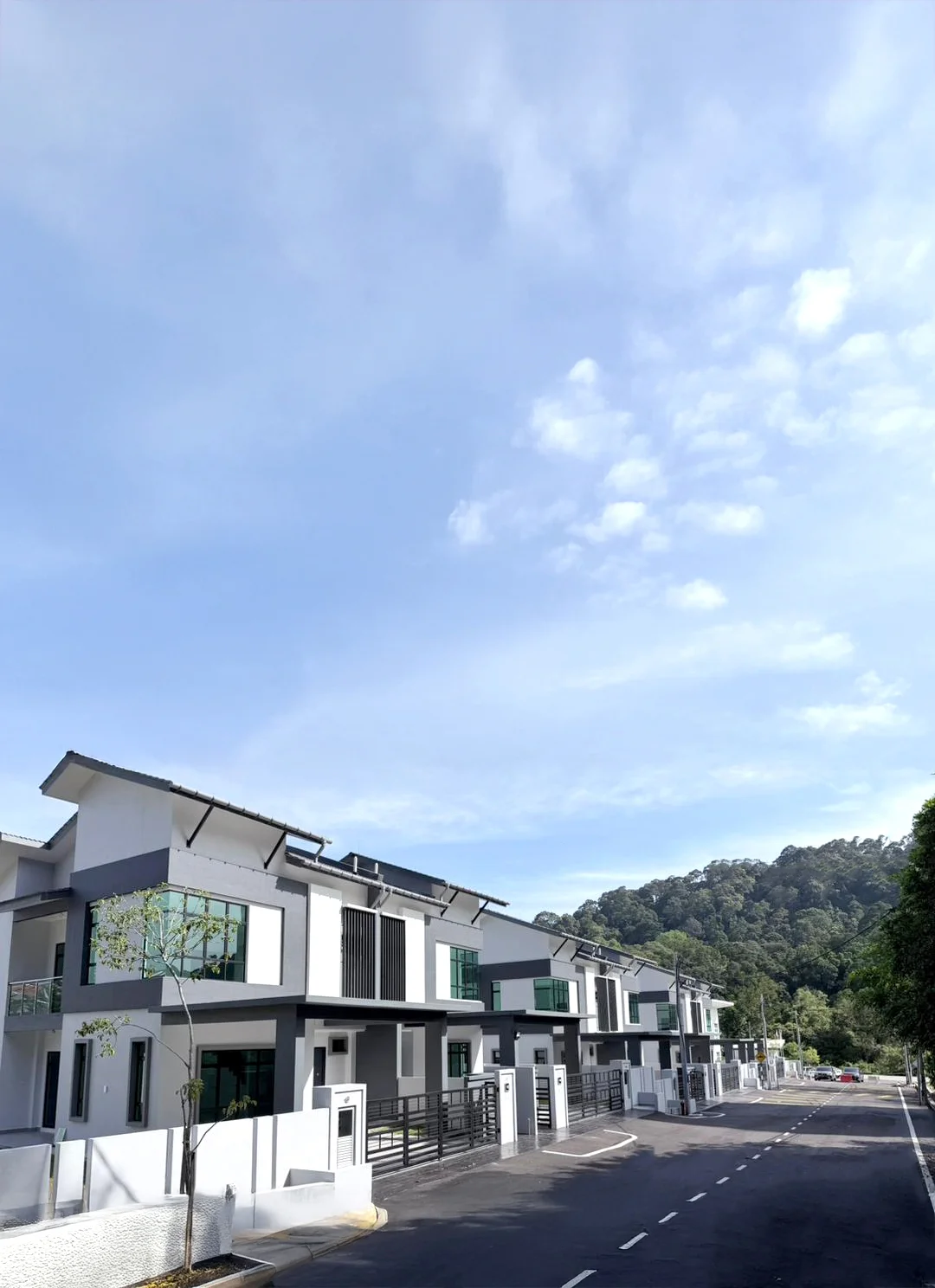 Exterior type: linked terrace house; features: white painted facade, black window frames, flat roof, two-storey, manicured lawn, paved driveway, surrounded by greenery, balconies with glass railings; style: modern.